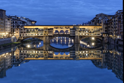 Arch bridge over river in city at night