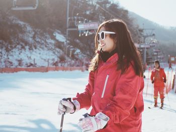 Side view of young woman skiing on snow covered field