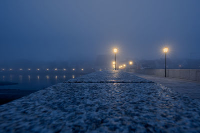 Surface level of illuminated street against sky at night