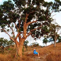 Full length of woman standing on tree trunk