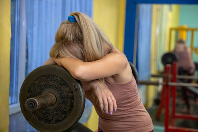 Midsection of woman holding dumbbell in gym