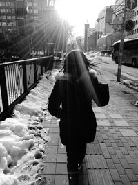 Rear view of woman walking on street in winter