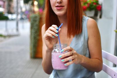 Young woman holding smart phone on street