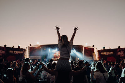 Rear view of people enjoying music concert against sky