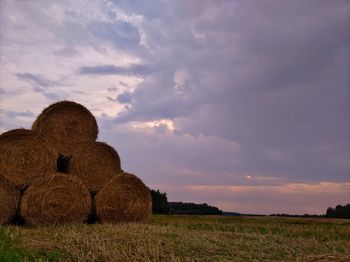 Hay bales on field against sky during sunset