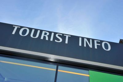 Low angle view of information sign against blue sky