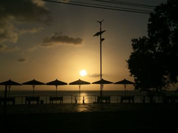 Silhouette beach by sea against sky during sunset