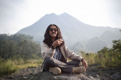 Relax and enjoy a cigarette on a rock with a view of mount merapi