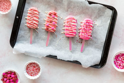 Valentine cakesicles decorated with candy melt drizzle and sprinkles.