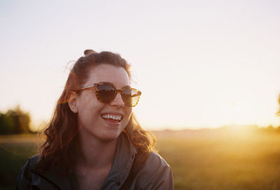 Portrait of smiling young woman on field against clear sky