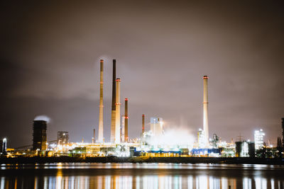 Illuminated factory against sky at night