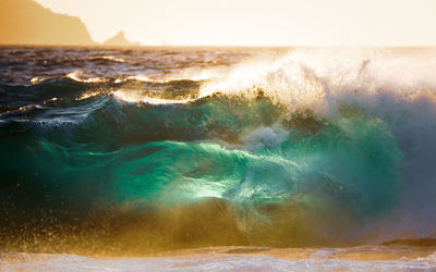 Sea waves splashing on shore against sky