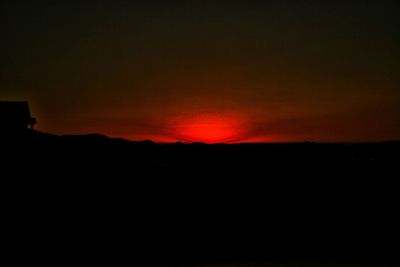 Silhouette landscape against dramatic sky during sunset