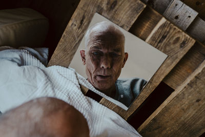 Directly above shot of senior man looking in mirror at home
