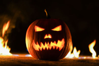 Illuminated jack o lantern with fire in background at night