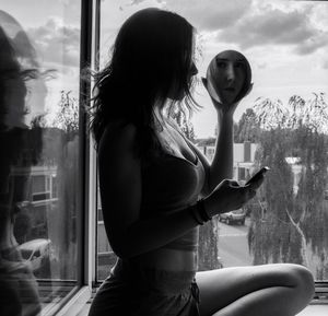 Side view of woman with reflection on glass window