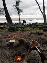 Bonfire by rocks on land against sky