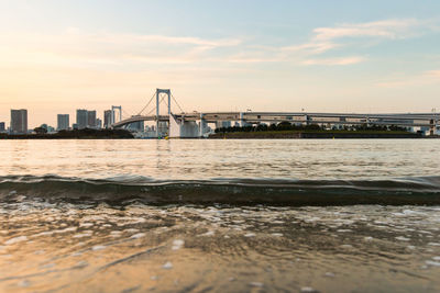 View of suspension bridge in city at sunset