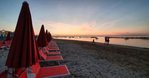 People on beach against sky during sunset