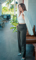 Full length of woman standing by potted plant