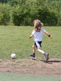 Rear view of girl playing soccer on field