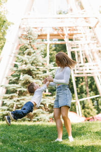 Caucasian mom circles her little son, holding in her hands, on a summer walk in the park