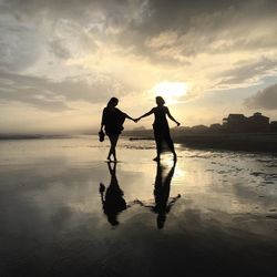 Woman standing on beach at sunset