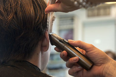 Close-up of hairdresser cutting hair of man