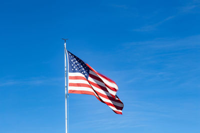 Low angle view of flag against blue sky