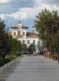 Street amidst trees and buildings against sky