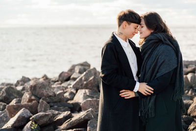 Young couple standing on rock by sea
