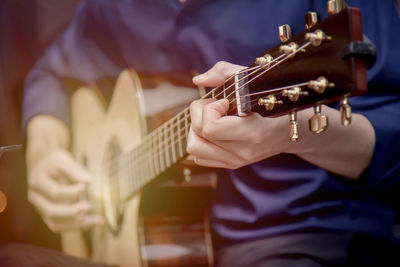 Midsection of man playing guitar