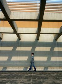 Full length side view of man walking by wall