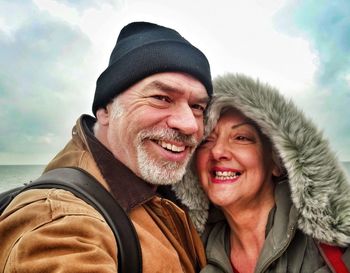 Cheerful mature couple wearing warm clothing at beach