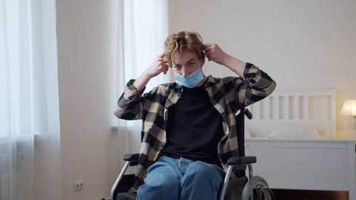 Portrait of man wearing mask sitting on wheelchair