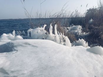 Snow covered land and sea against sky