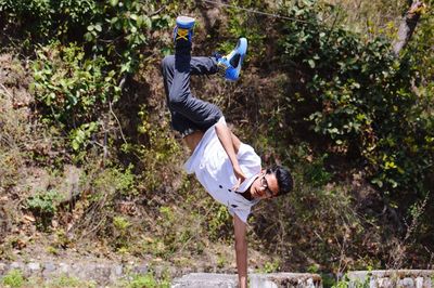 Portrait of young man doing handstand on field