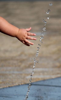 Cropped image of child reaching towards water