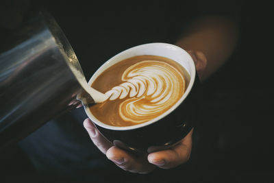 Cropped hand making coffee at cafe