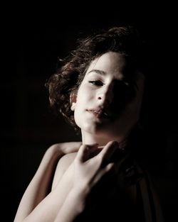 Close-up portrait of young woman against black background