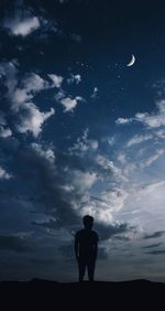 Rear view of silhouette man standing on field against sky