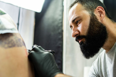 Close-up of artist tattooing customer in studio