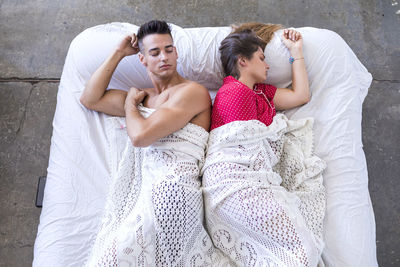 High angle view of man and woman sleeping back to back on bed
