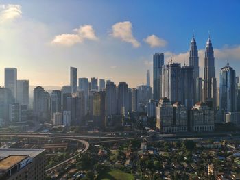 Aerial view of buildings in city against blue sky