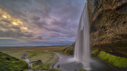 Scenic view of waterfall against sky during sunset