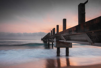 Pier over sea against sky during sunset