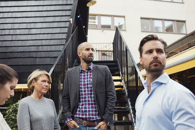 Business people looking away while standing outside log cabin
