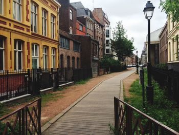 Footpath amidst buildings against sky