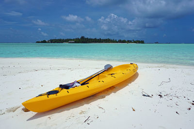 Yellow boat on beach against sky