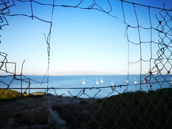 Close-up of barbed wire fence against sky